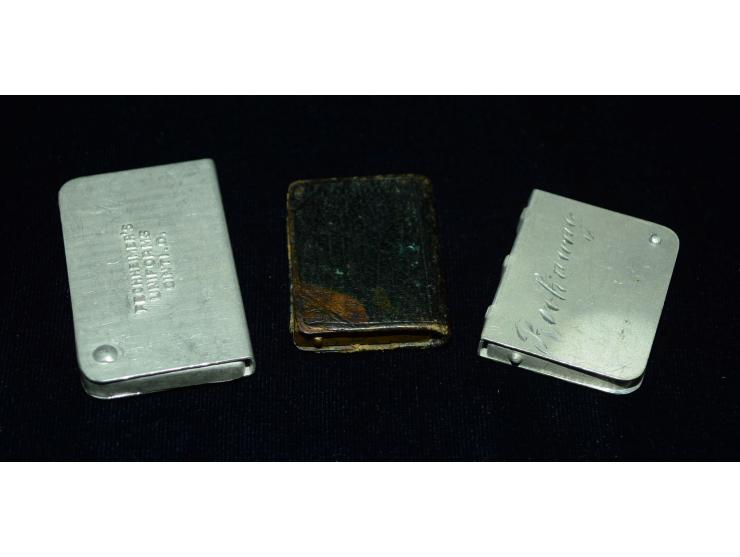 Kleines Lot mit drei Briefmarkendosen in Buchform, zwei aus Aluminium gefertigt, eine aus Bronze mit Lederüberzug. Verschiede