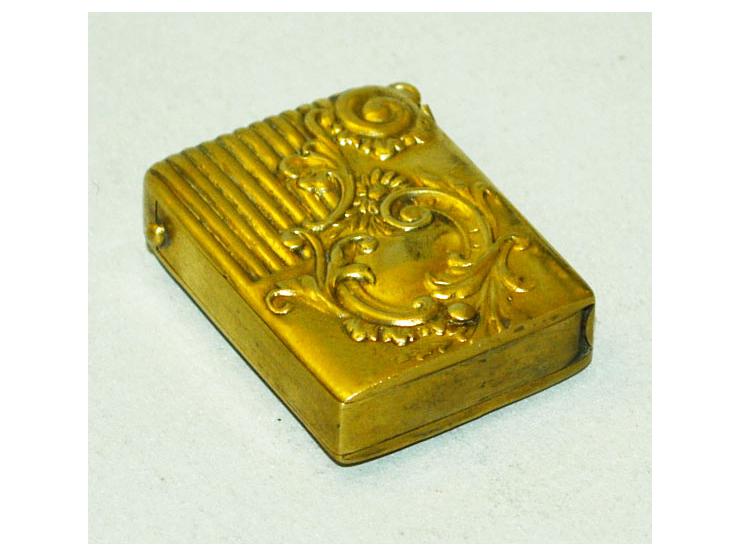 Kleine Briefmarkendose in goldfarbenem Metal, erhaben gearbeitetes Design, kleine Öse zur Nutzung als Anhänger. Gebrauchsspur