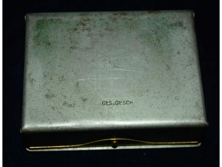Kleine Briefmarkendose aus Bronze oder Gelbguss und grau gefärbtem Metal. Die Dose hat vier innenliegenden Briefmarkenfächer 