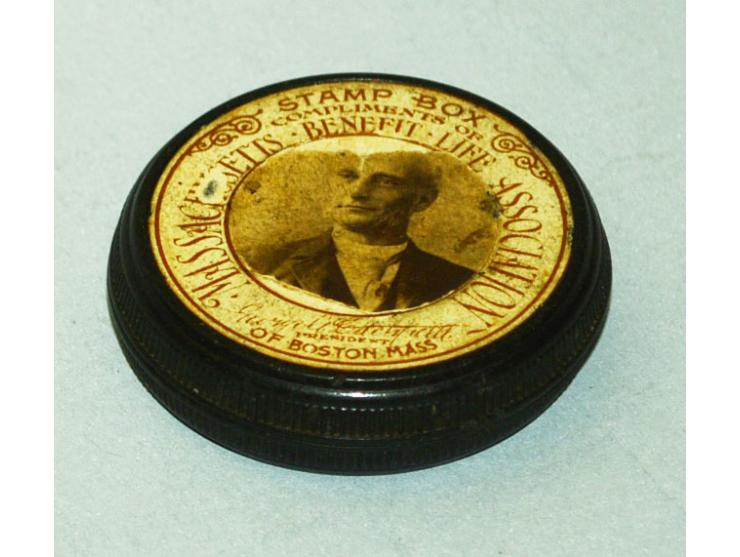 Briefmarkendose in runder Ausführung aus Vulcanit hergestellt, datiert 1893. Die Dose war als Werbegeschenk der "Massachusett
